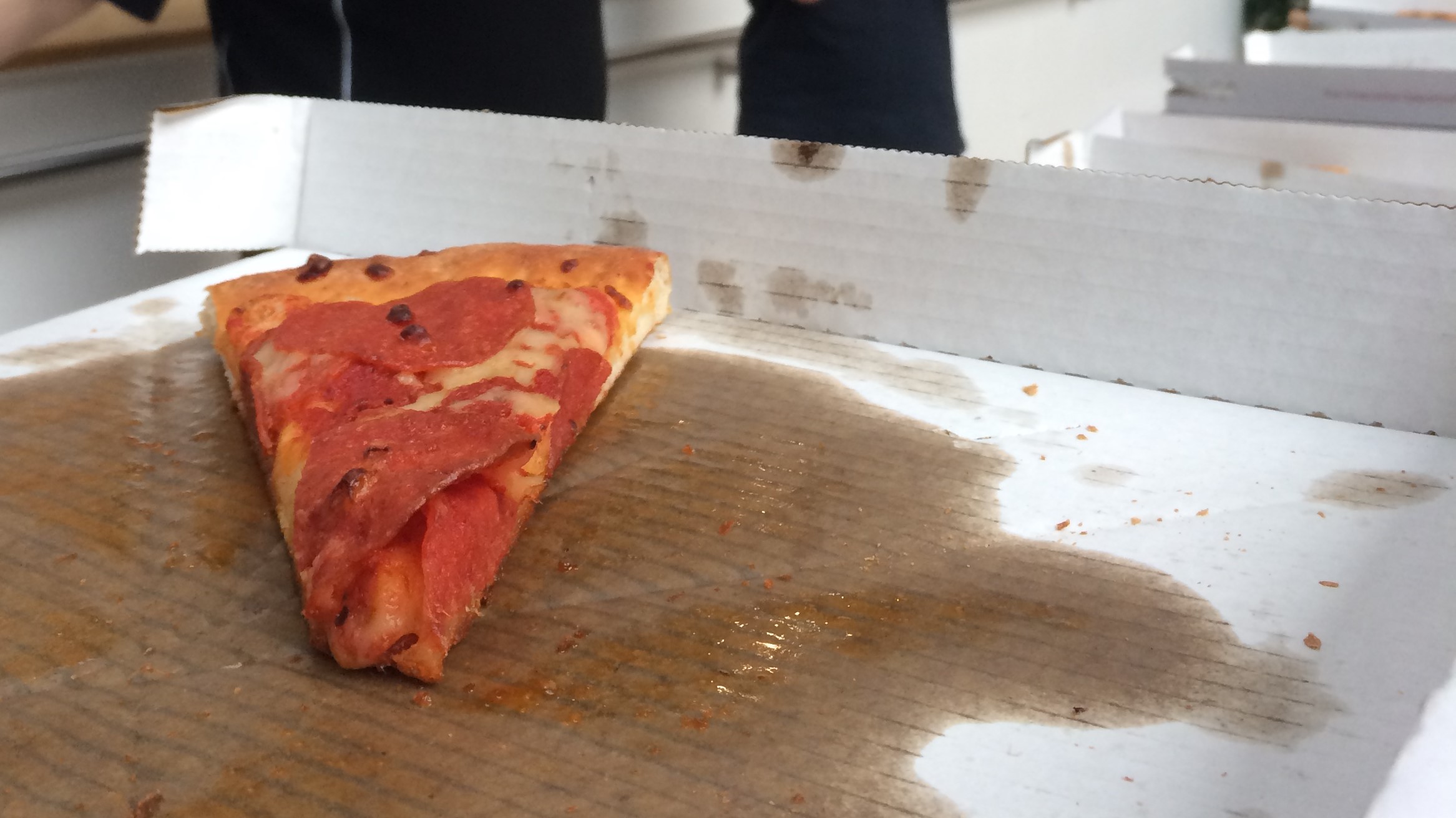 A lone slice of pizza in a greasy box.